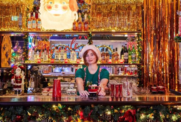 This is a picture of the Miracle Christmas-themed cocktail bar at Henrietta Hotel where the whole bar is lit up with decorations and the bartender is in an elf costume.