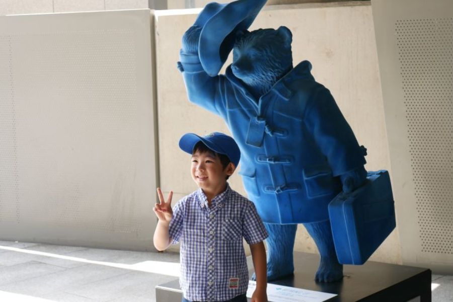A child posing with the Paddington Bear statue during one of the top kid-friendly London Tours