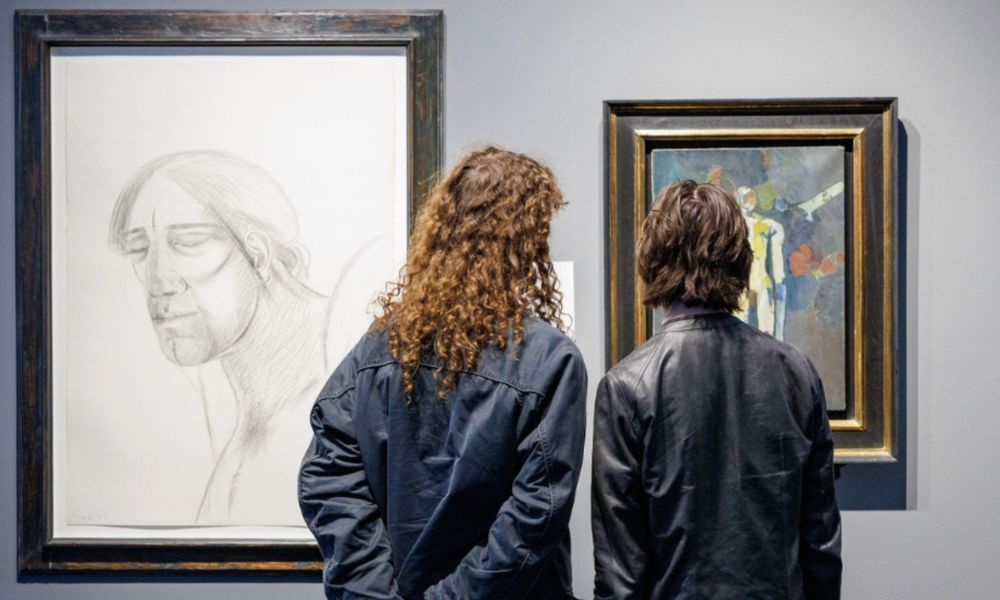 This is an image of two women looking at portraits of art hanging on the wall.