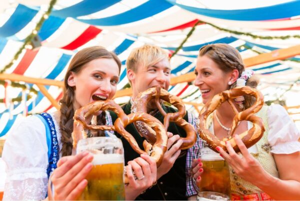This is an image of three people eating pretzels and holding big pints of beer for Oktoberfest.