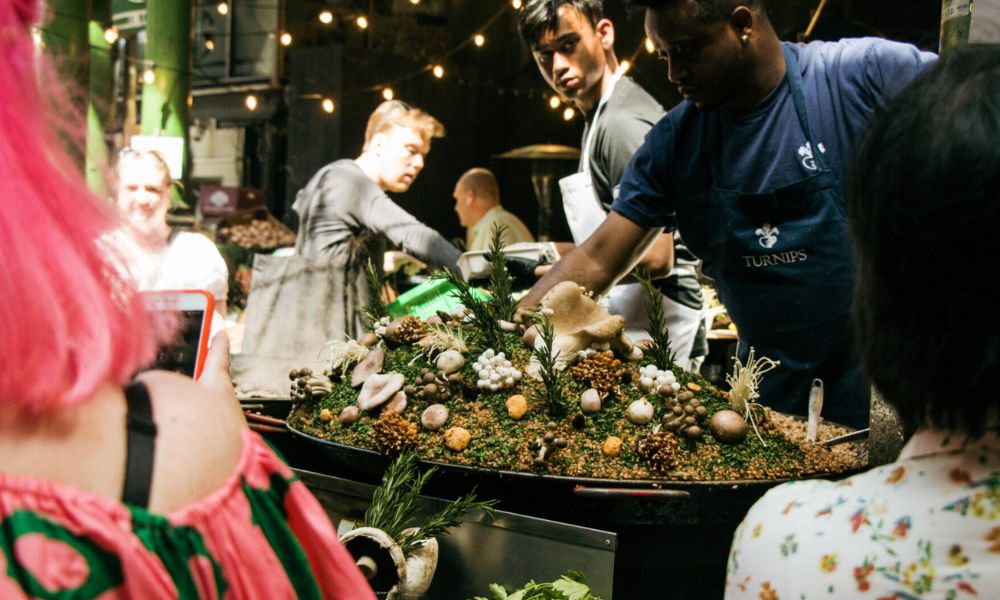 This is an image of a group of people standing around a paella stall at Borough Market.