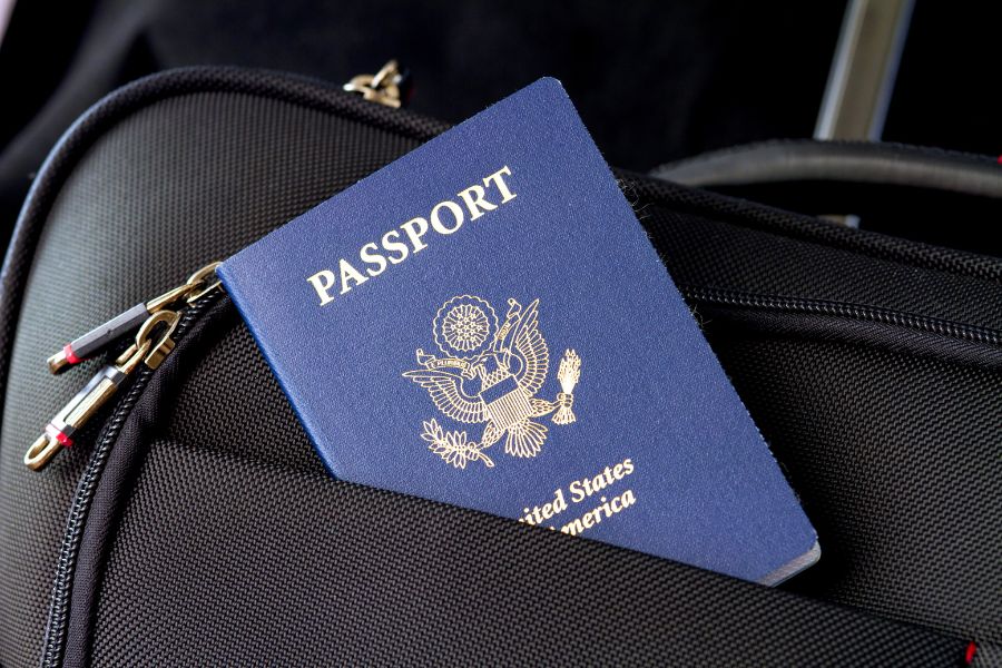 A United States passport tucked into the front pocket of a black suitcase