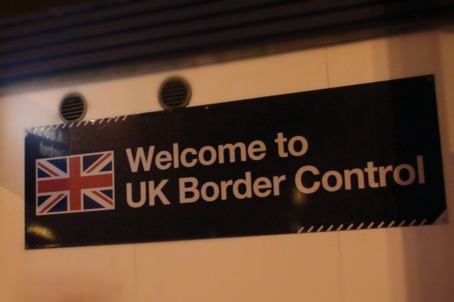 A sign reading "Welcome to UK Border Control" with a Union Jack flag, photographed at Heathrow Airport