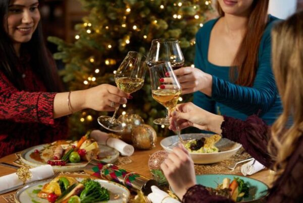 This is an image of a table of friends sharing a Christmas roast and clinking their glasses together.