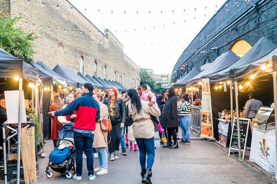 Black-owned Hackney street market in London in April lined with tents and vendors selling food and wares. 