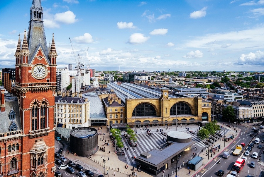 This captivating aerial photo provides a panoramic view of both Kings Cross and St. Pancras stations, showcasing their intricate architecture and bustling railway tracks in stunning detail.