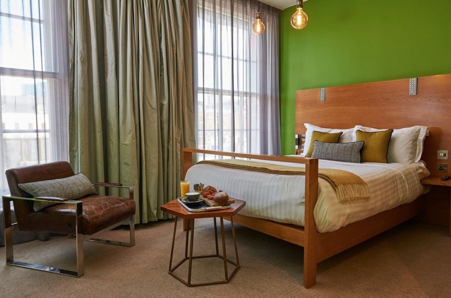 This is an image of a cool hotel bedroom with a green wall.