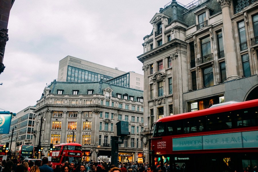 This is an image of a busy Oxford Street in Central London. There are many double-decker red buses to be seen, as well as lots of people on foot walking.