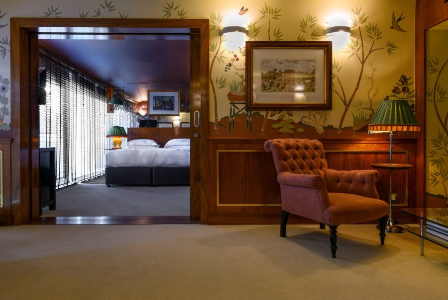 This is an image of a fancy hotel suite with a bedroom that opens up into a living space.