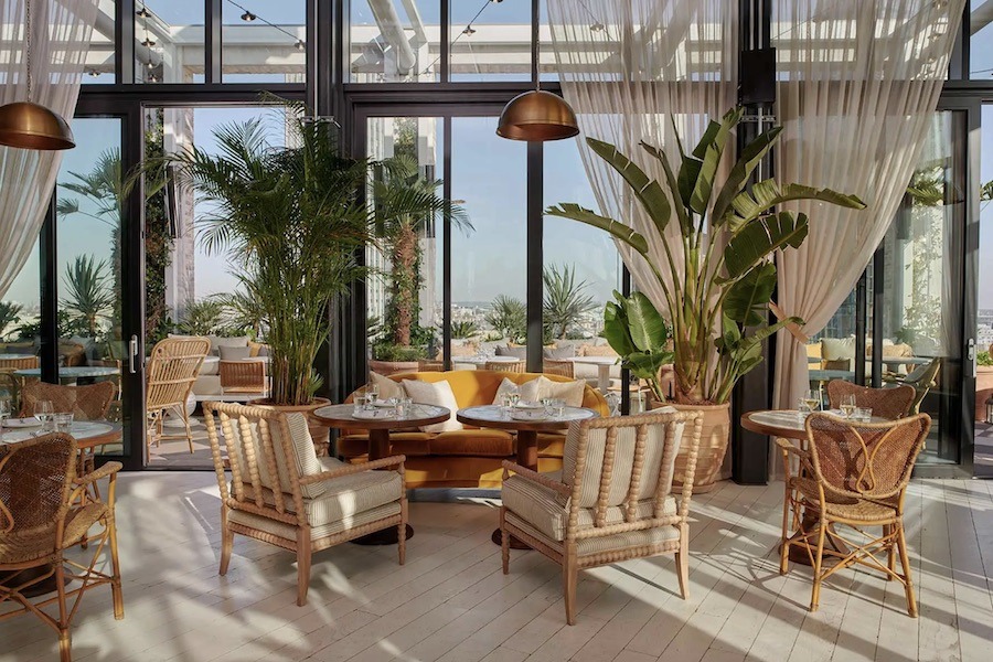 This is an image of a beautiful rooftop with beachy, coastal interiors and lovely plants around the room, with a big open deck window.