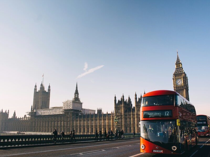 This image is of a double-decker bus driving over a bridge. You can see Big Ben and the Parliament houses behind it in the distance.