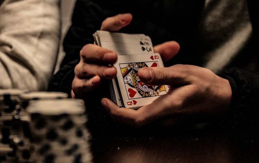 This is an image of a man shuffling a deck of playing cards. Street games are a common scam to avoid when visiting London.