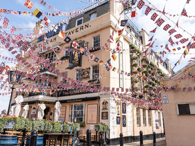 This is an image of a riverside pub with a bunch of world flags hung up around.