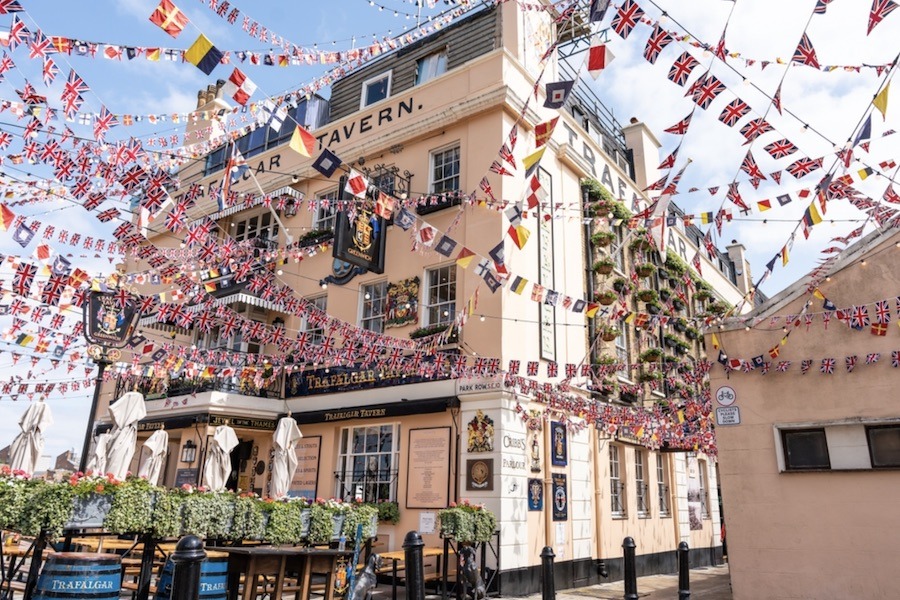 This is an image of a riverside pub with a bunch of world flags hung up around.