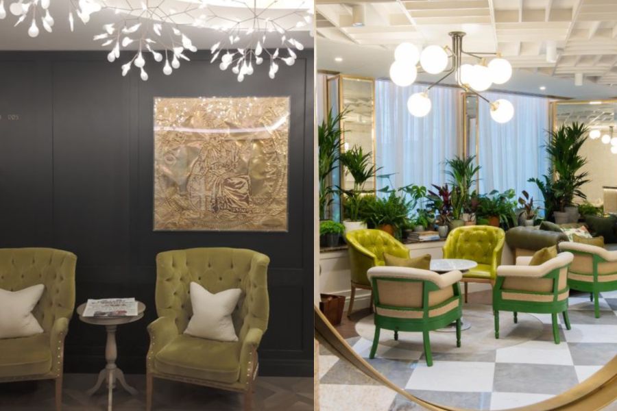 Two interior views of Vintry & Mercer hotel: on the left, a pair of olive green velvet tufted armchairs beneath a sculptural branch-like chandelier in front of a dark wall with a large gold artwork; on the right, a bright lounge area with green and cream chairs around a marble table, surrounded by lush tropical plants and globe pendant lights.