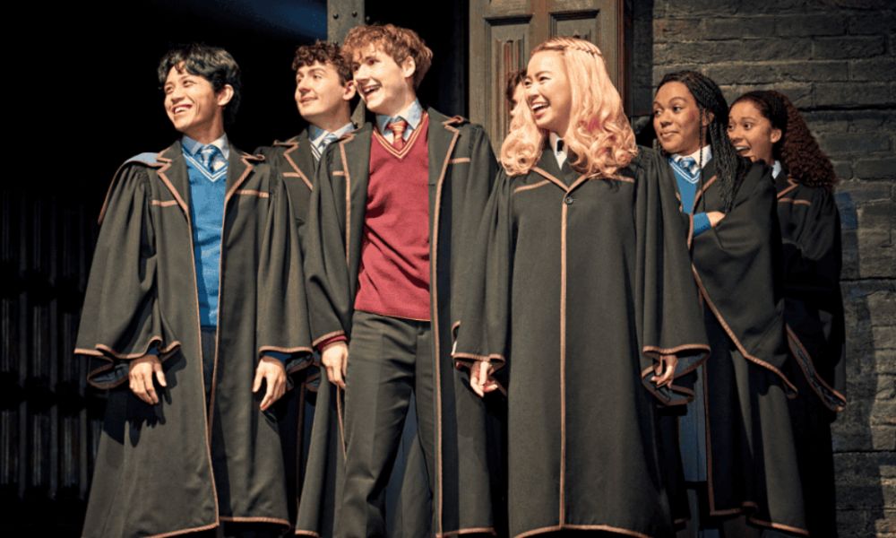 Best West End shows in London: This is an image of a group of Hogwarts students in robes stand in a row, facing forward with happy expressions