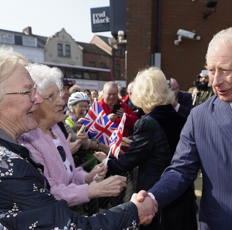 King Charles shaking hands with two elderly ladies.