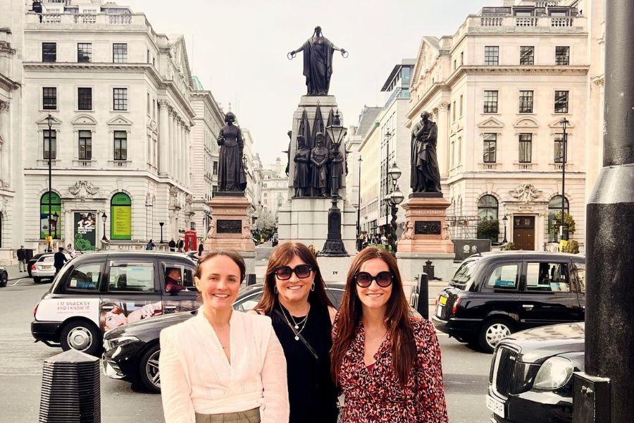 This is an image of three women on a Women in London tour. They are standing in front of a statue.